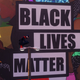 Miles perched atop a street light in front of a Black Lives Matter mural.